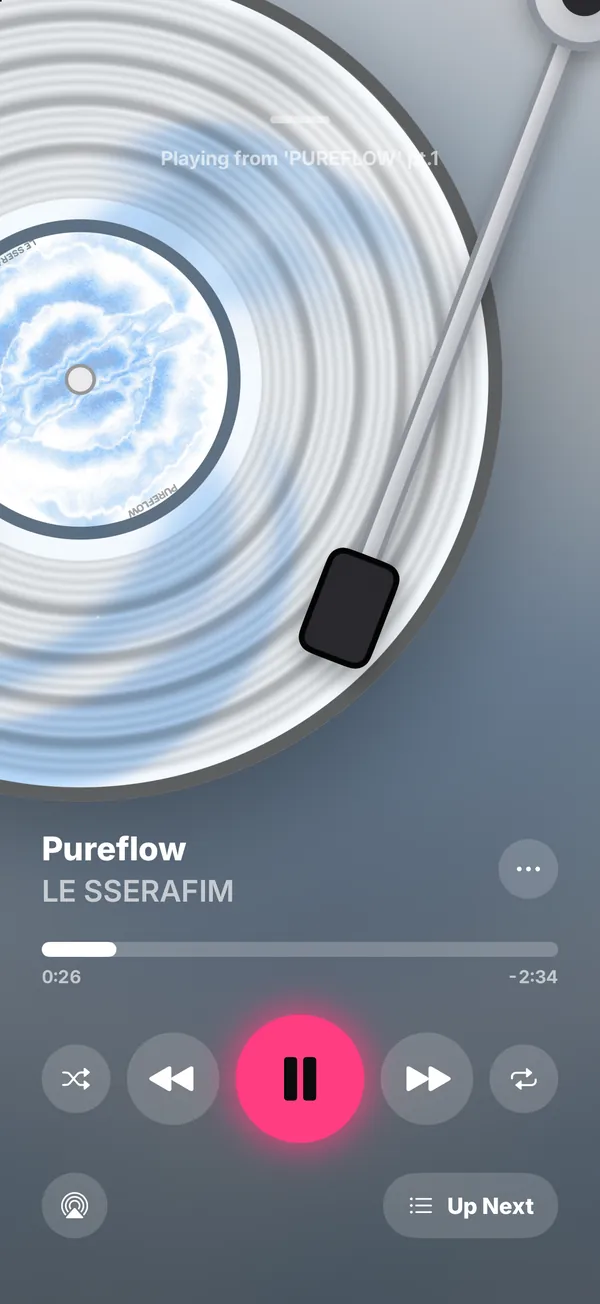 PocaPal 전체 화면 플레이어: LE SSERAFIM 'PUREFLOW' pt.1의 Pureflow가 앨범 색으로 찍은 레코드 위에서 톤암을 내린 채 재생되고, 흐린 앨범 아트 위에 재생 막대, 재생 버튼, AirPlay, Up Next가 있어요.